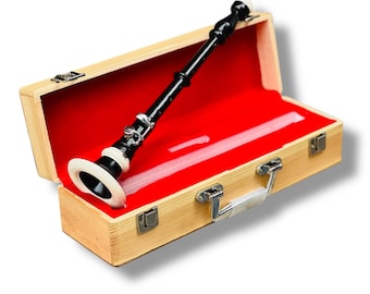 Può includere: Un oboe nero e bianco è riposto in una custodia di legno aperta con un rivestimento in velluto rosso. L'oboe ha chiavi argentate e dettagli bianchi. La custodia ha una maniglia e chiusure argentate.