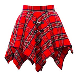 Puede incluir: Falda a cuadros roja con un dobladillo asimétrico. La falda presenta un patrón de tartán clásico en rojo, negro, amarillo y verde. Tiene hebillas negras decorativas en la parte delantera, añadiendo un toque de estilo.