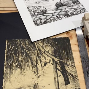 May include: A black and white drawing of a forest scene with trees, rocks, and a small boat in the distance. The drawing is on a light brown paper.