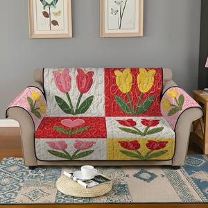 May include: A quilted sofa cover featuring a patchwork design with tulip motifs. The cover showcases squares of white, red, and yellow, each adorned with embroidered tulips in pink, red, and yellow. The cover also has armrest covers with tulip designs.