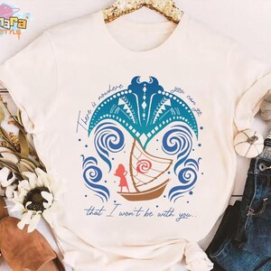 May include: A cream-colored short-sleeve t-shirt featuring a graphic of a brown sailboat, a red silhouette of a person, and a blue manta ray design. The text reads, There is nowhere you can go that I won't be with you, in a blue cursive script.