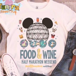 May include: White t-shirt featuring a graphic design for the Food & Wine Half Marathon Weekend. The design includes a geometric sphere with Mickey Mouse ears, food icons, and the text "FOOD & WINE" and "HALF MARATHON WEEKEND".