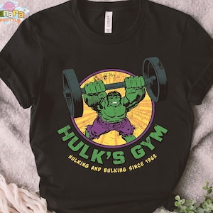May include: Black t-shirt featuring a graphic of the Hulk lifting weights inside a yellow and purple circle. The text "Hulk's Gym" and "Hulking and Bulking Since 1962" are printed in green and yellow.