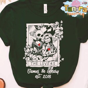 May include: Dark green t-shirt featuring a black and white illustration of Jack and Sally from The Nightmare Before Christmas, with the text "THE LOVERS" and "James & Mary est. 2018". The design is framed by floral elements.