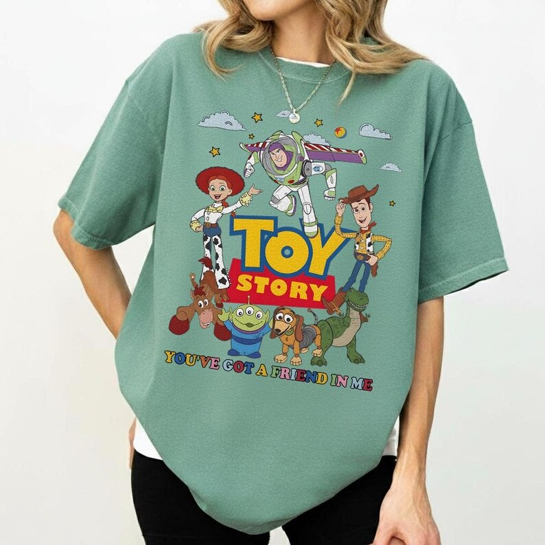 Puede incluir: Camiseta verde salvia con un gr&aacute;fico colorido de personajes de la pel&iacute;cula "Toy Story". El dise&ntilde;o incluye a Woody, Buzz Lightyear, Jessie y otros personajes, con las palabras "Toy Story" y "You've Got a Friend in Me."