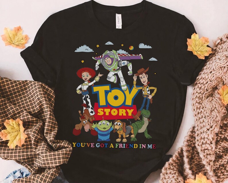 Puede incluir: Camiseta negra con un gr&aacute;fico colorido de personajes de la pel&iacute;cula animada "Toy Story". El dise&ntilde;o incluye a Buzz Lightyear, Woody, Jessie y otros personajes, con las palabras "Toy Story" y "You've Got a Friend in Me."