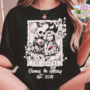 May include: Black t-shirt featuring a black and white tarot card design with Jack Skellington and Sally from The Nightmare Before Christmas. The card reads "The Lovers" with the names "James & Mary" and the year "est. 2018".