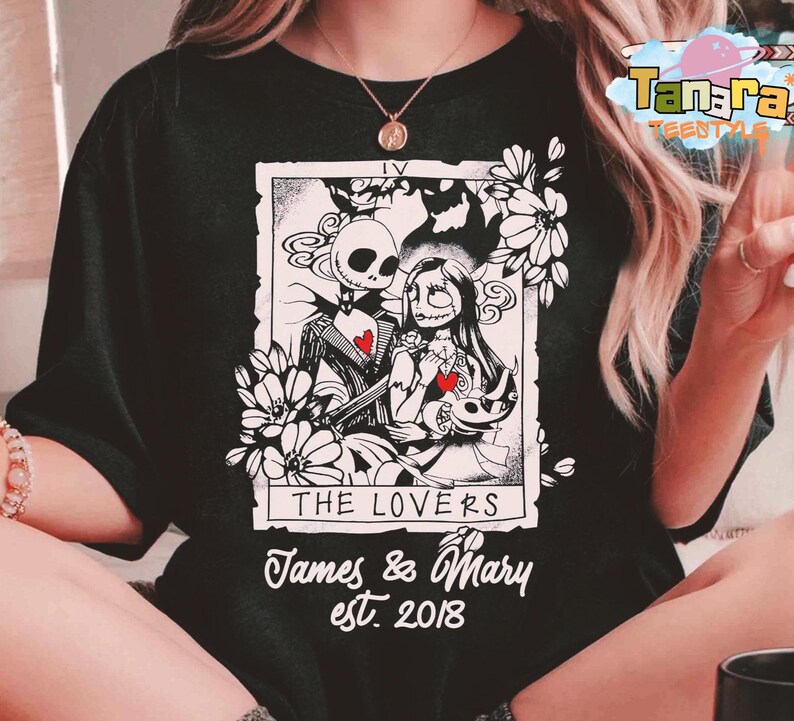 May include: Black t-shirt featuring a black and white tarot card design with Jack Skellington and Sally from The Nightmare Before Christmas. The card reads "The Lovers" with the names "James & Mary" and the year "est. 2018".