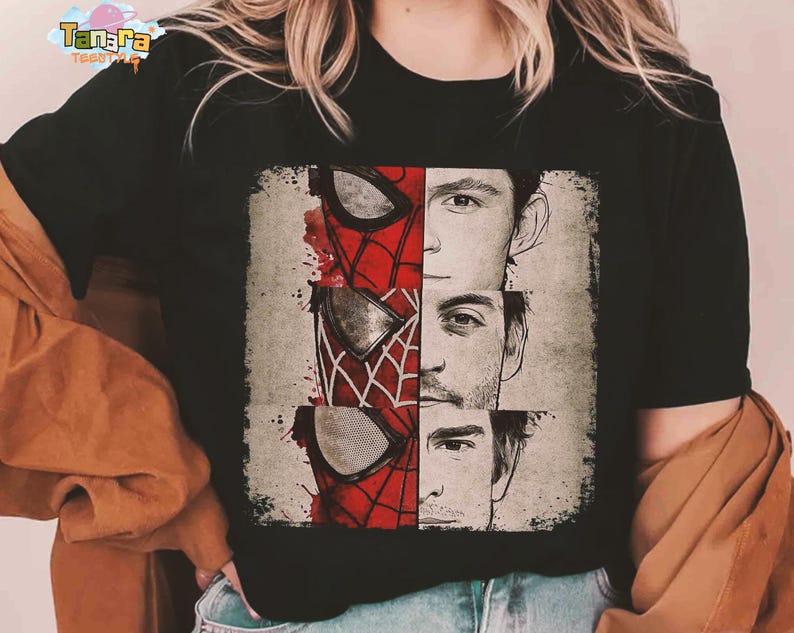 Puede incluir: Camiseta negra con un dise&ntilde;o gr&aacute;fico de tres caras de Spider-Man, cada una representando a un actor diferente. El dise&ntilde;o incluye la m&aacute;scara de Spider-Man en rojo y negro, con las caras de los actores en escala de grises. La camiseta tiene el texto "Tanara Tees".