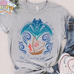 May include: A heather gray short-sleeve t-shirt featuring a graphic of a brown sailboat with a red spiral sail, a blue manta ray, and blue swirling waves. The text reads, There is nowhere you can go that I won't be with you.