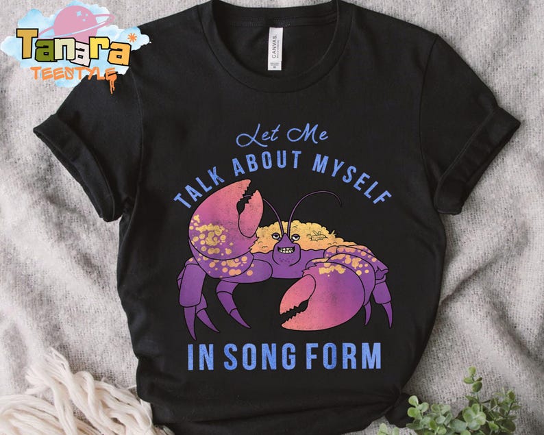 Puede incluir: Camiseta negra con una ilustraci&oacute;n de un cangrejo de dibujos animados. El cangrejo es morado y rosa con detalles dorados. El texto de la camiseta dice "Let Me Talk About Myself In Song Form" en azul. La camiseta es de material suave.