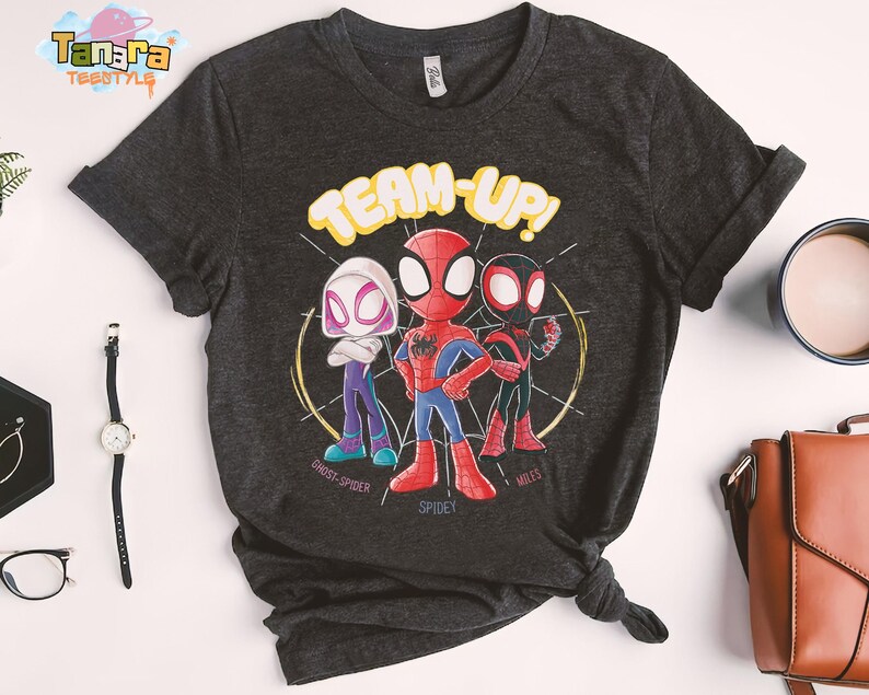 May include: Dark gray t-shirt featuring a graphic of three cartoon Spider-Man characters with the words "TEAM-UP!". The characters include Ghost-Spider, Spidey, and Miles, each in their signature colors.