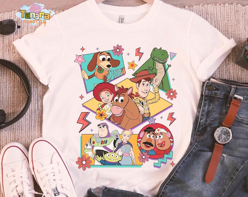Peut inclure: T-shirt blanc avec un graphisme color&eacute; des personnages de Toy Story. Le design pr&eacute;sente Woody, Buzz Lightyear, Rex et d'autres personnages dans un style r&eacute;tro. Le t-shirt est fait d'une mati&egrave;re douce.