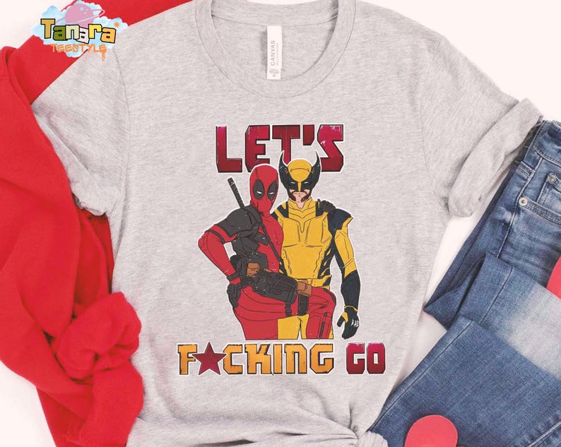 Puede incluir: Camiseta gris claro con ilustraciones de Deadpool y Wolverine. El texto "LET'S F*CKING GO" est&aacute; impreso en rojo y naranja. La camiseta se combina con vaqueros azules y una camisa roja de manga larga.