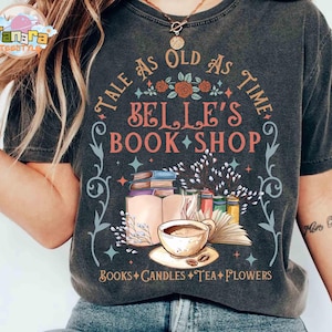 May include: Dark gray t-shirt with a graphic design featuring the text "Tale as Old as Time Belle's Book Shop." The design includes books, a teacup, flowers, and the words "Books, Candles, Tea, Flowers."