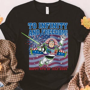 May include: Black t-shirt featuring a graphic of Buzz Lightyear in a patriotic design with the text "TO INFINITY AND FREEDOM!" and "HAPPY 4TH OF JULY 2026". The design includes the American flag and fireworks.