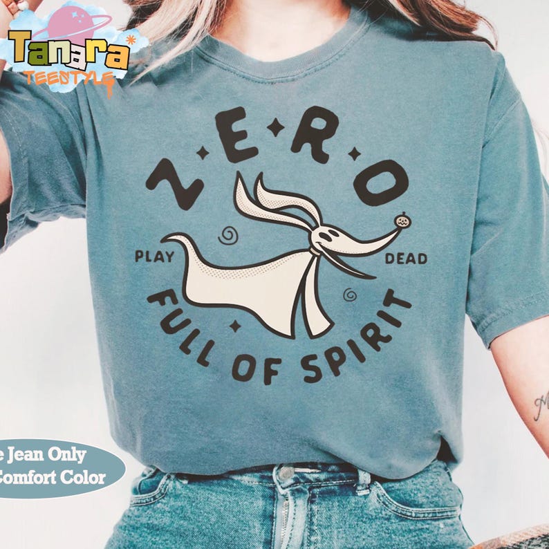 Puede incluir: Una camiseta verde azulado con un dise&ntilde;o de Zero de The Nightmare Before Christmas. El dise&ntilde;o incluye el texto "ZERO" encima del personaje, con "PLAY" y "DEAD" a cada lado, y "FULL OF SPIRIT" debajo. La camiseta es Comfort Color.
