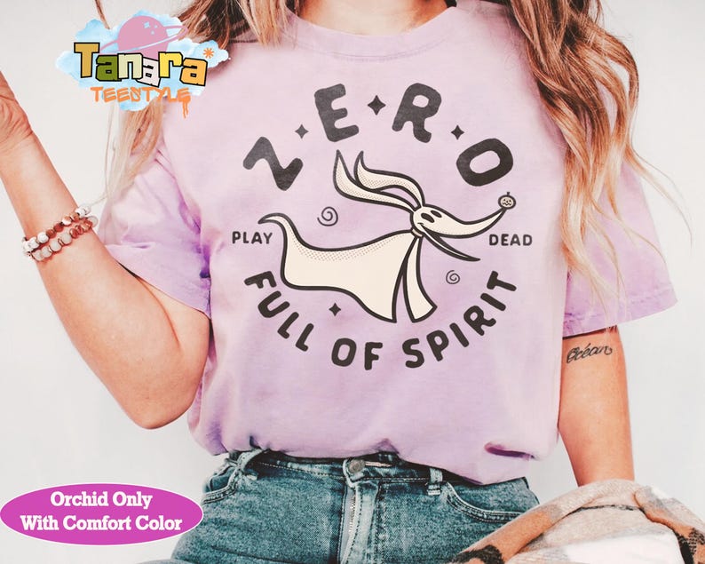 Puede incluir: Una camiseta de color lila claro con un dise&ntilde;o de Zero de Pesadilla antes de Navidad. El dise&ntilde;o incluye las palabras "ZERO", "PLAY", "DEAD" y "FULL OF SPIRIT". La camiseta es de color confort.