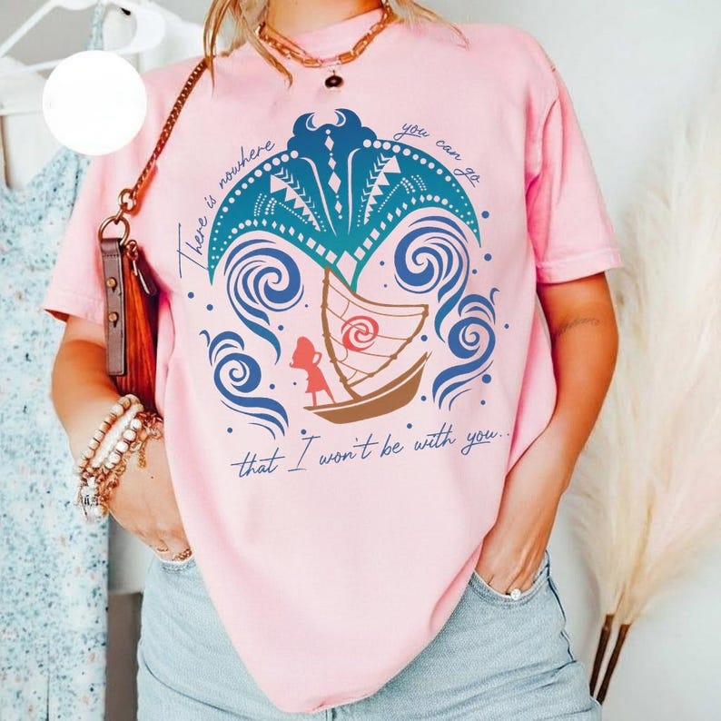 May include: A light pink short-sleeve t-shirt featuring a graphic of a boat on blue waves with a stylized manta ray above it. The text reads, There is nowhere you can go that I won't be with you, surrounding the central illustration.