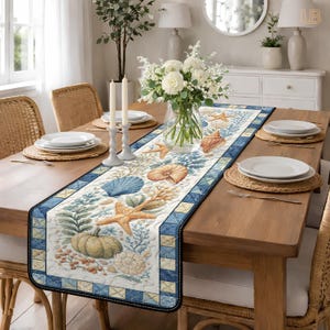 May include: A rectangular table runner with a coastal theme. The runner features a quilted design with seashells, starfish, and coral in shades of blue, beige, and green. The border is a blue and white checkered pattern. The runner is placed on a wooden table.