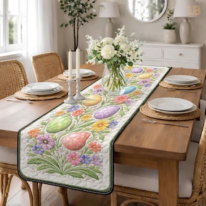 May include: A rectangular Easter table runner with a floral and egg design. The runner features pastel-colored eggs and flowers in shades of pink, yellow, blue, and purple. The edges are trimmed with a black border. The runner is placed on a wooden table.