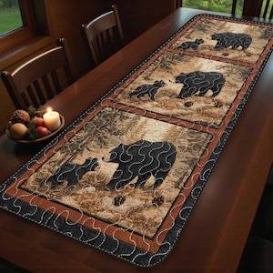 May include: Quilted table runner featuring a forest scene with black bears and their cubs. The runner has a brown and black border with a stitched design. The bears are depicted in a stylized, textured pattern, set against a backdrop of trees and foliage.