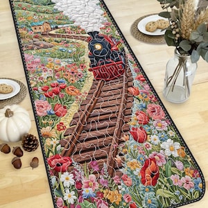 May include: A rectangular floral runner depicting a train on tracks, surrounded by vibrant flowers. The train is red and black, with white smoke. The runner has a black border and is placed on a wooden table. The runner's length is approximately 150 cm.