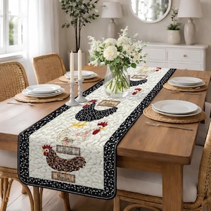 May include: A quilted table runner featuring a cream background with black polka dot borders. The runner showcases appliqued chickens with names like "Daisy" and "Rosie." The design includes floral accents and a farmhouse aesthetic, perfect for kitchen or dining decor.