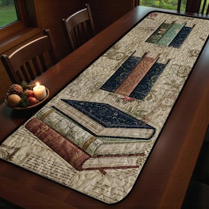 Könnte beinhalten: Gesteppter Tischläufer mit einem Design aus Büchern in Blau, Braun und Burgunderrot. Der Läufer hat einen cremefarbenen Hintergrund mit einem Vintage-Schrift- und Blumenmuster. Er ist mit einem schwarzen Rand versehen.