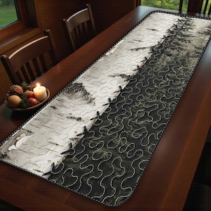 May include: A long, rectangular table runner with a nature-inspired design. One side features a birch tree bark pattern, while the other has a dark green forest print. The two sides are joined with black stitching.