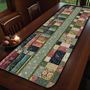 May include: A rectangular table runner with a patchwork design. The runner features a variety of fabrics in shades of blue, green, pink, and beige. A central stripe with floral patterns and a green border runs down the center. The runner is placed on a wooden table.
