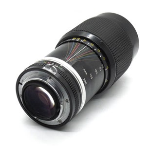 Puede incluir: Un objetivo de c&aacute;mara negro con un anillo plateado y una escala en blanco y negro. La escala muestra la distancia focal en mil&iacute;metros, de 85 a 200.