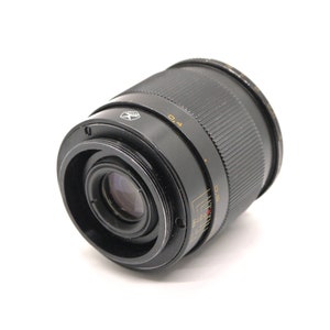 K&ouml;nnte beinhalten: Ein schwarzes Kameraobjektiv mit einem silbernen Ring und Markierungen. Das Objektiv hat einen schwarzen Gummiring um die Vorderseite.