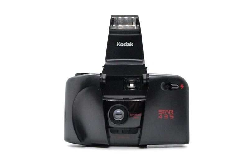 May include: A black Kodak Star 435 film camera with a built-in flash. The camera has a red "EXTREME ZOOM" label and a red "STAR 435" label.