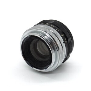 May include: A silver and black camera lens with an aperture ring that reads "5.6 8 9 11 16 22 27 32".