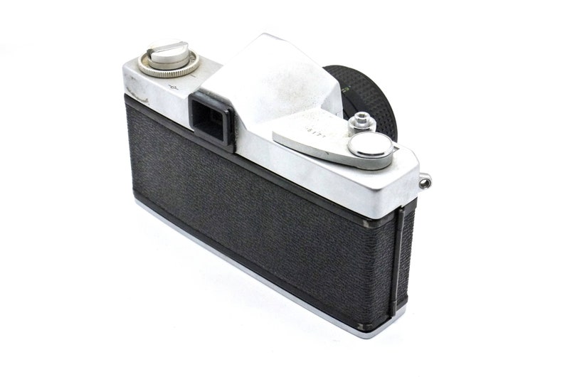 May include: A silver and black 35mm film camera with a black leather covering. The camera has a silver top with a black viewfinder and a silver lens cap.