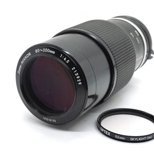 Puede incluir: Un objetivo Nikon Zoom-Nikkor 80-200mm 1:4.5 negro con un filtro Optex Skylight (1A) de 52 mm negro.