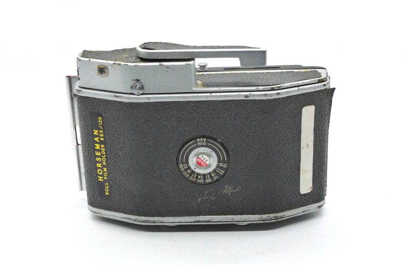 Puede incluir: Un porta rollo de pel&iacute;cula Horseman negro y plateado para pel&iacute;cula 6x/120. El porta rollo tiene una ventana circular con un logotipo "Kodak" rojo y un dial blanco y negro con marcas para diferentes velocidades de pel&iacute;cula.