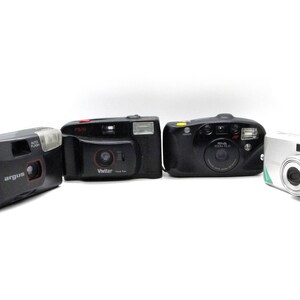Puede incluir: Cuatro c&aacute;maras de pel&iacute;cula compactas diferentes, incluyendo una Argus negra, una Vivitar negra, una Minolta Zoom Plus negra y una Ziss plateada.