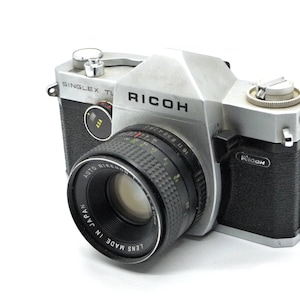 May include: A silver and black Ricoh Singleflex TL camera with a black lens that reads "Lens Made in Japan Auto Rikenon 50mm f1.9".