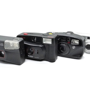Puede incluir: Cuatro c&aacute;maras de pel&iacute;cula compactas diferentes, que incluyen una Argus negra, una Vivitar negra, una Minolta negra y una Ziss plateada. Las c&aacute;maras est&aacute;n en buen estado y tienen una variedad de funciones.