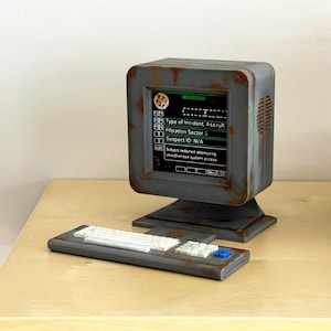 May include: A miniature computer model with a weathered, rusted gray finish. The screen displays text including Type of Incident, Assault, Filtration Sector 5, and Suspect ID: N/A. A matching keyboard with white keys and a blue button sits in front.
