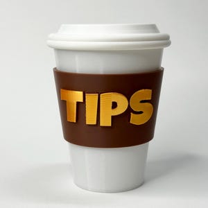 Könnte beinhalten: Eine weiße Keramik-Kaffeetasse mit einer braunen Silikonhülle. Auf der Hülle steht das Wort "TIPS" in goldfarbenen Buchstaben. Die Tasse hat einen weißen Deckel und ist für Heißgetränke konzipiert.
