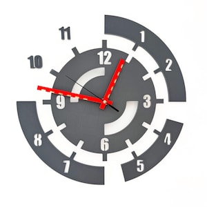 May include: A grey and white clock with red hands. The clock face is divided into sections with numbers 1 through 12. The clock is designed in a modern style.
