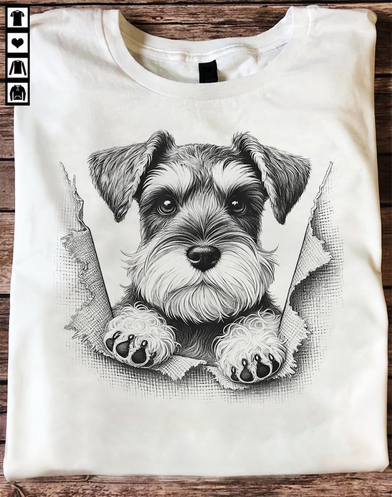 May include: White t-shirt with a black and white Schnauzer dog illustration. The dog appears to be breaking through the fabric. The design showcases the dog's face and paws. The t-shirt has a crew neck.