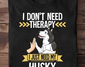 May include: Black t-shirt with the text "I DON'T NEED THERAPY I JUST NEED MY HUSKY." The design features a cartoon husky dog giving a high-five to a human hand. The dog is black, white, and gray.