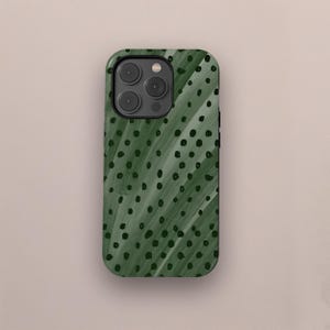 Könnte beinhalten: Dunkelgrüne Handyhülle mit einem Muster aus diagonalen Pinselstrichen und kleinen schwarzen Punkten. Die Hülle hat eine glänzende Oberfläche und einen Kameraausschnitt.