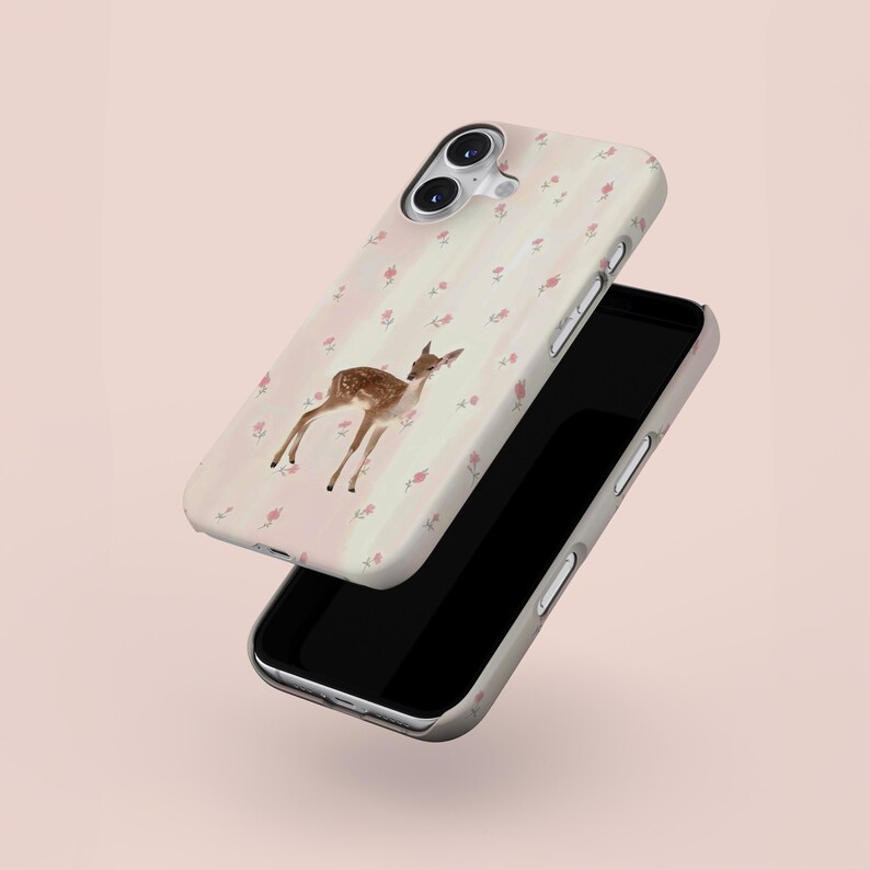 May include: A phone case with a deer illustration and floral design. The case has a light pink striped background with small pink flowers. The phone's screen is black. The case is designed for a smartphone.