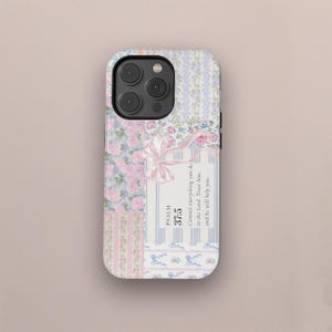 Puede incluir: Una funda blanca para iPhone con un diseño de patchwork que presenta patrones florales, rayas y una cita del Salmo 37:5: "Encomienda al Señor tu camino, confía en él, y él actuará."