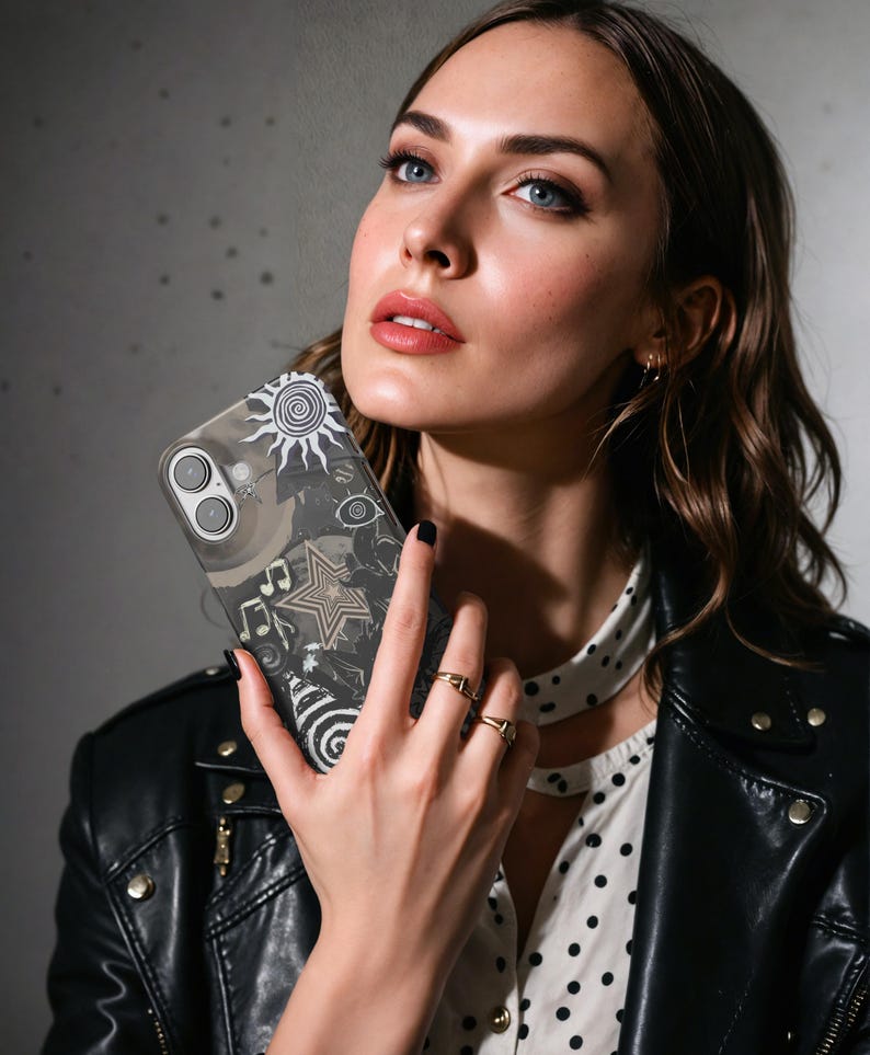 Puede incluir: Funda transparente para tel&eacute;fono con un dise&ntilde;o gr&aacute;fico en blanco y negro que presenta un sol, un ojo, una estrella y notas musicales. La funda se sostiene frente a una persona que lleva una chaqueta de cuero negra y una camisa blanca de lunares.